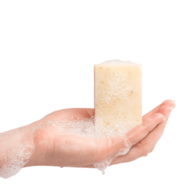 A hand holding a wet bar of soap with bubbles and subs 